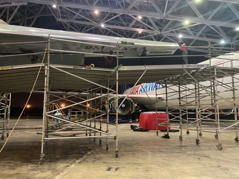 Scaffold towers under an aircraft wing in a hangar