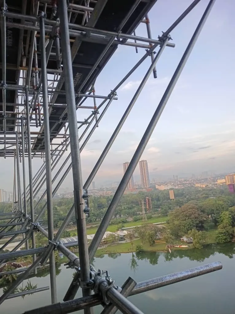 Tubular scaffold along a high-rise facade over a lake
